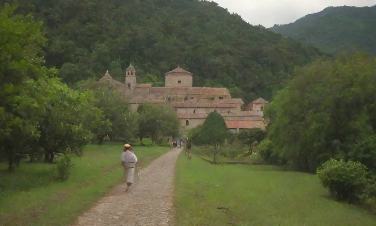 El sereno Monasterio de San Juan de Ortega enclavado en exuberante vegetación, con peregrinos caminando cerca.