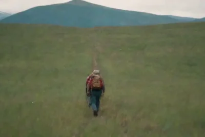 Un funámbulo caminando sobre una cuerda floja en un paisaje de montaña