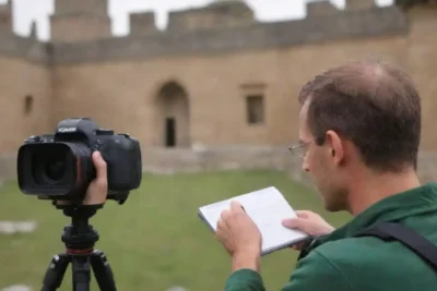 Un fotógrafo capturando imágenes de un sitio del Patrimonio Mundial de la UNESCO con un cuaderno y cámara cerca.