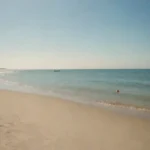 Escena de playa tranquila en un día de semana con pocas tumbonas y cielos claros.