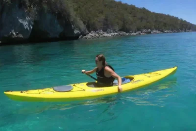 Gente en kayak y snorkeling en aguas cristalinas.
