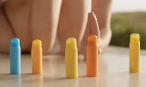 Una persona que compara diferentes botellas de protector solar bajo la luz del sol.