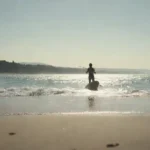 Persona disfrutando de deportes acuáticos bajo el sol con una hermosa playa en el fondo.