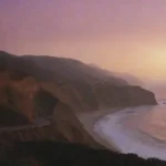 Una carretera costera pintoresca a lo largo del Océano Pacífico con hitos icónicos y puestas de sol vibrantes.