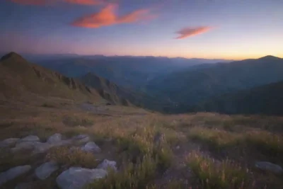 Luces brillantes y colores danzantes en el cielo sobre una majestuosa cordillera.