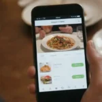 Una persona que navega por opciones de restaurante en una aplicación móvil mientras considera diferentes opciones de comedor.