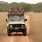 Guía en un safari explicando la fauna a un grupo de turistas en un vehículo 4x4.
