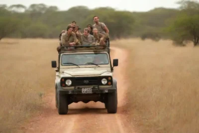 Guía en un safari explicando la fauna a un grupo de turistas en un vehículo 4x4.