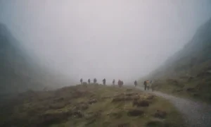 Un grupo de turistas despertardos explorando un sendero montañoso envuelto en niebla y luces brillantes.