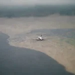 Pasajeros revisando un mapa y ajustando planos en el puerto mientras llueve.