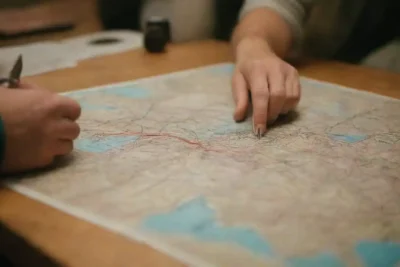 Mapa abierto en una mesa con un explorador planeando rutas alternas y menos frecuentadas.
