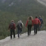 Grupo de jóvenes escalando una montaña con entusiasmo y un experimentado guía.