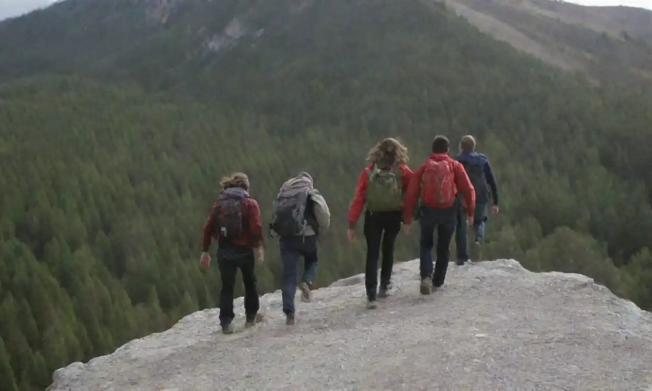 Grupo de jóvenes escalando una montaña con entusiasmo y un experimentado guía.