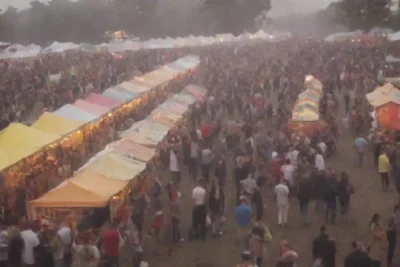 Crowd navegando por un festival vibrante con mapas y puestos de comida.